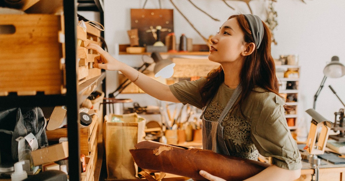 Young artisan woman works in a cozy studio crafting leather goods, showcasing creativity and craftsmanship.