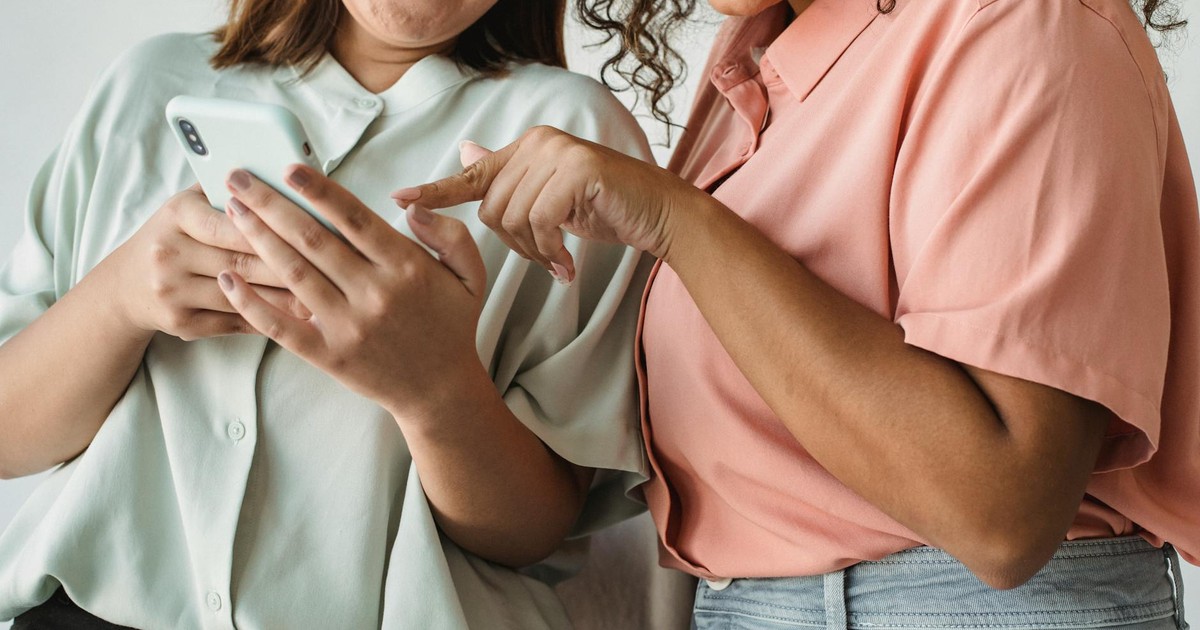 Close-up of two women interacting with a smartphone, smiling and engaging with technology.