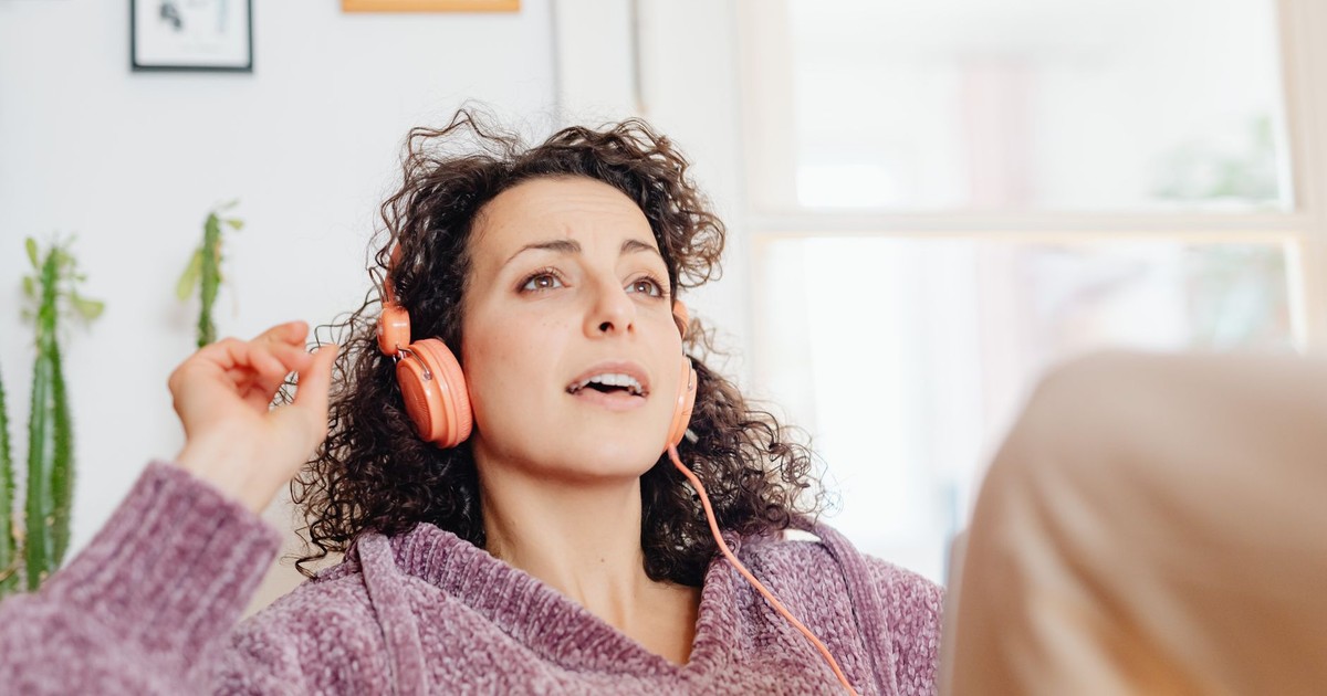 Young woman relaxing indoors, enjoying music with headphones, experiencing joy and relaxation.