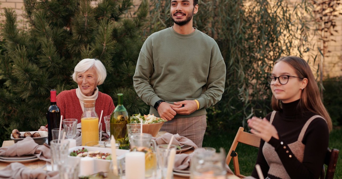 Cheerful family members having dinner party and spending time together in backyard in daytime