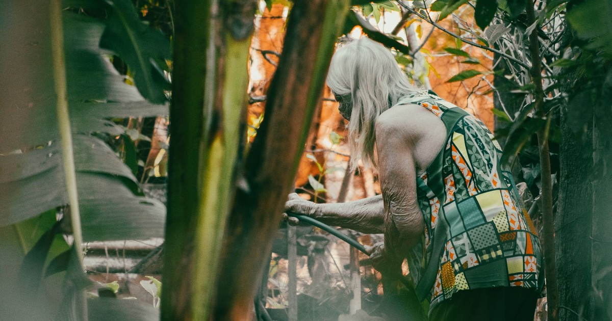 An elderly woman tends to her garden, creating a serene and fulfilling outdoor experience.
