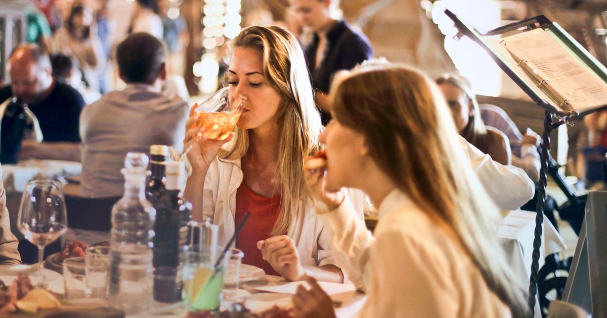 Friends dining in a cozy Italian restaurant, enjoying drinks and food in a lively atmosphere.