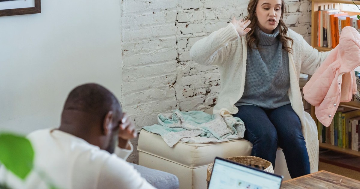 Irritated wife emotionally accused black husband and tired man covering face with hand and looking in laptop screen