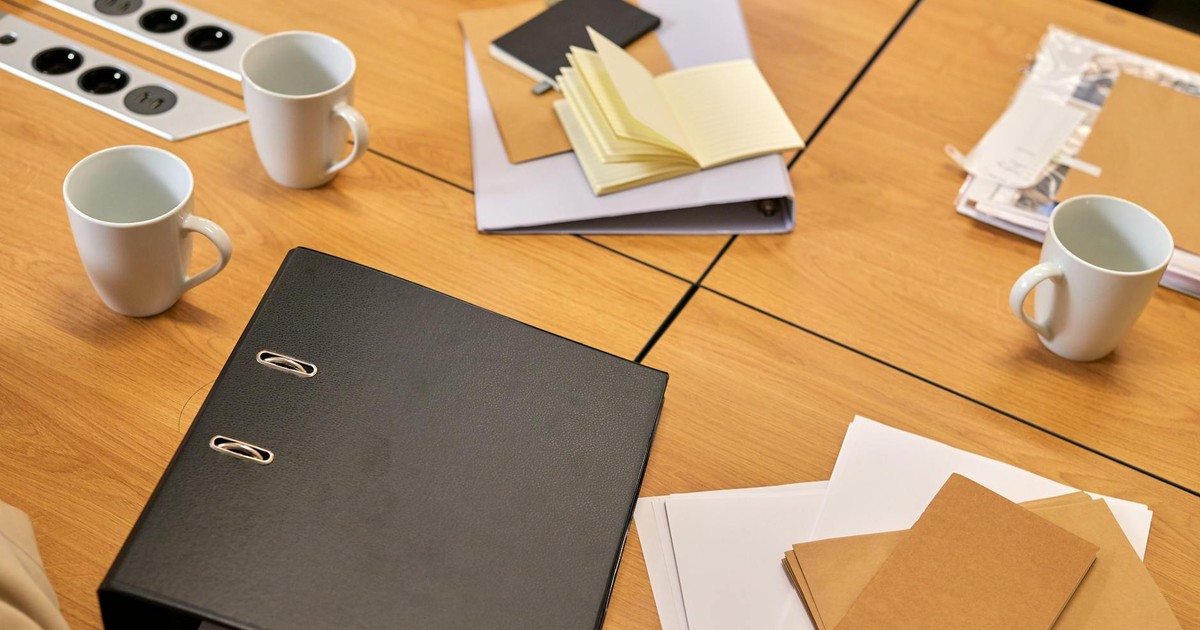 A neat office desk with binders, papers, and coffee mugs arranged neatly, offering a professional workspace vibe.