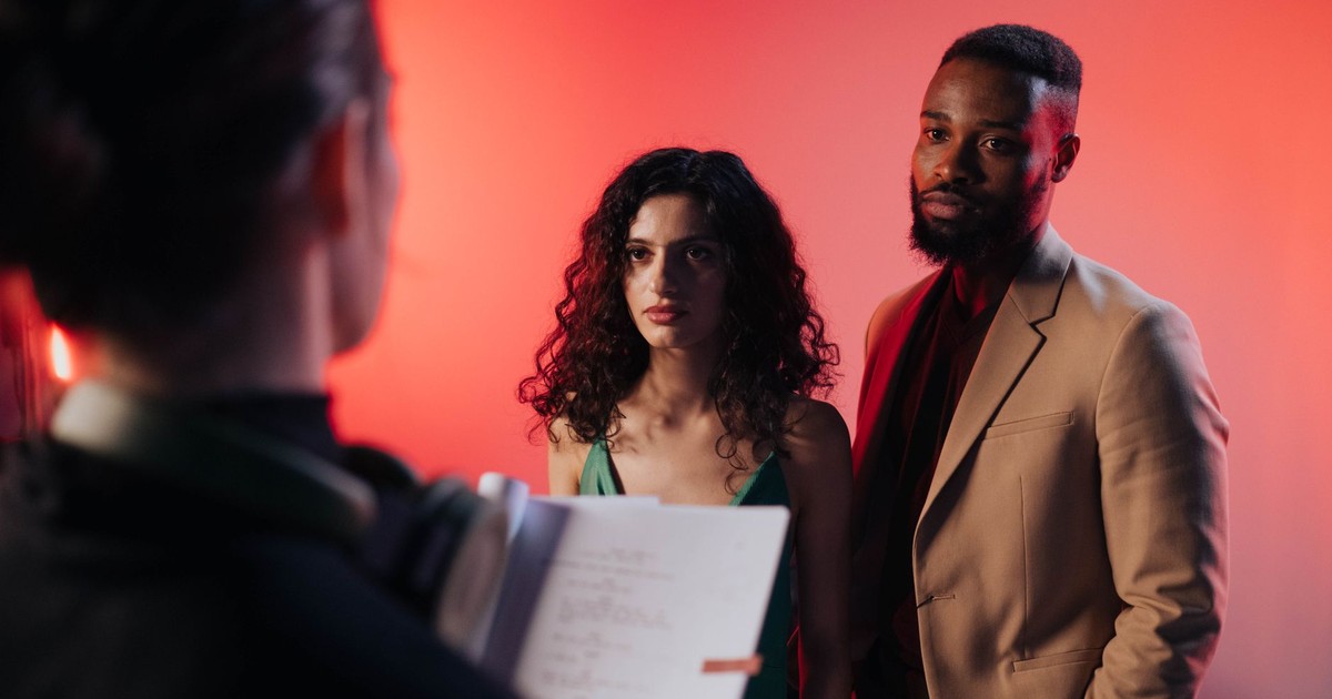 Couple reading script in a studio with warm lighting for film or theater production.