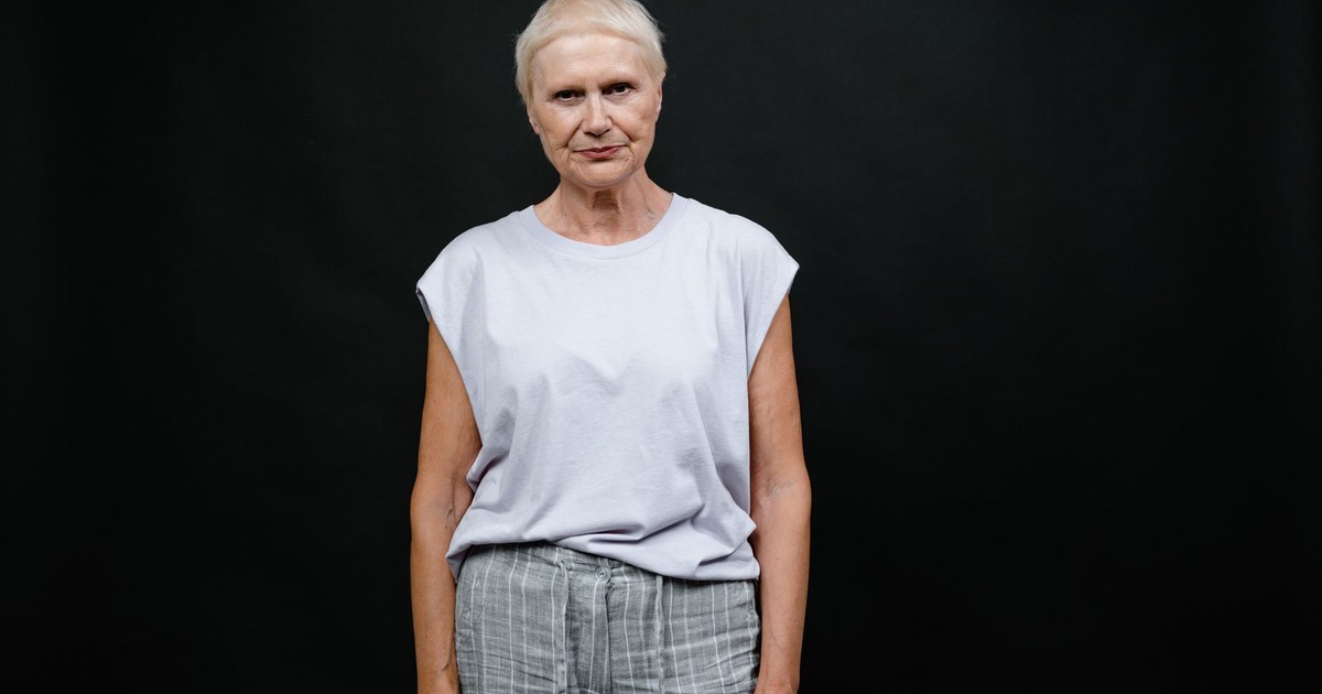 Portrait of a senior woman in a casual outfit against a black background, capturing individuality and expression.