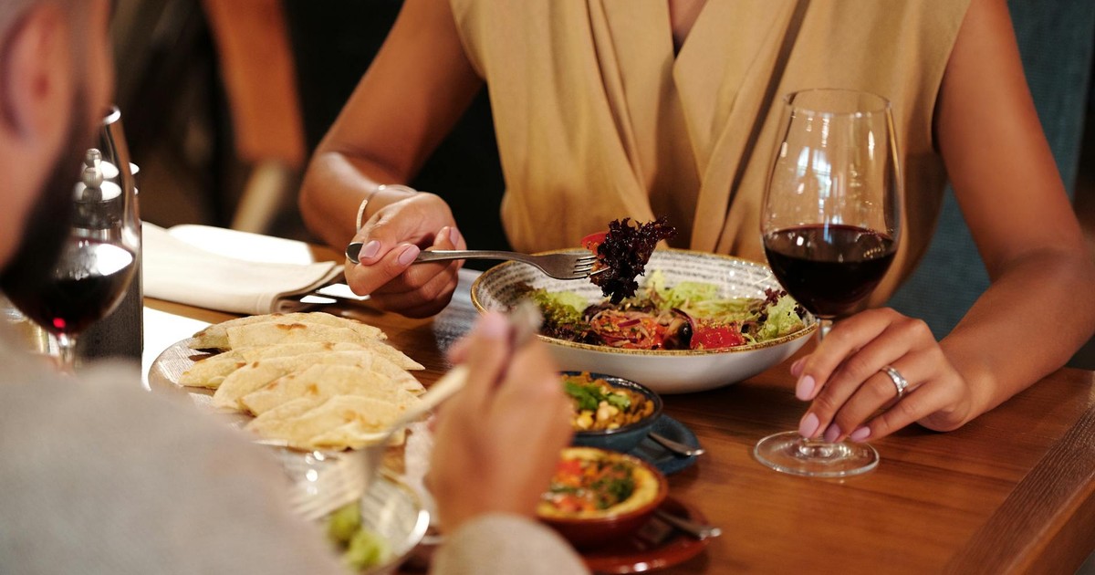 Couple enjoying a romantic dinner with wine and delicious meals at a cozy restaurant.