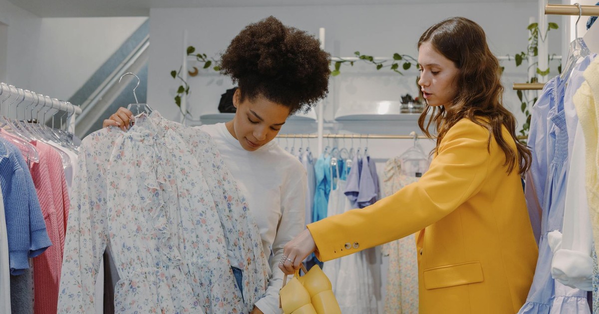 Two women shopping fashionably in a chic boutique with floral and yellow apparel.