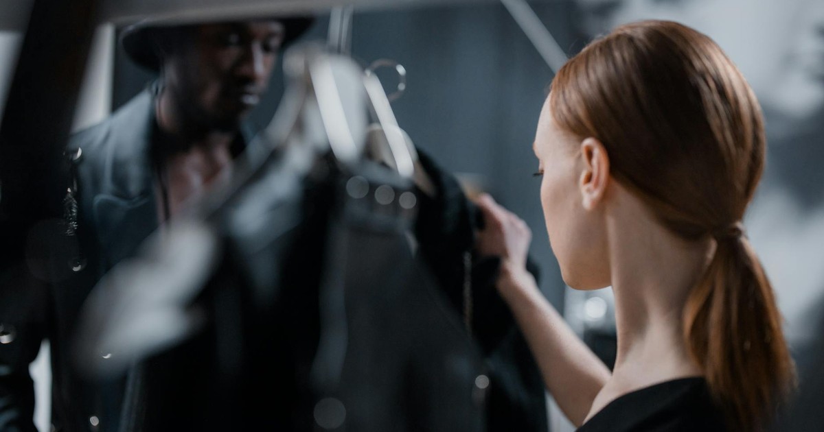 Fashion designer and model preparing for a studio photoshoot with elegant garments.