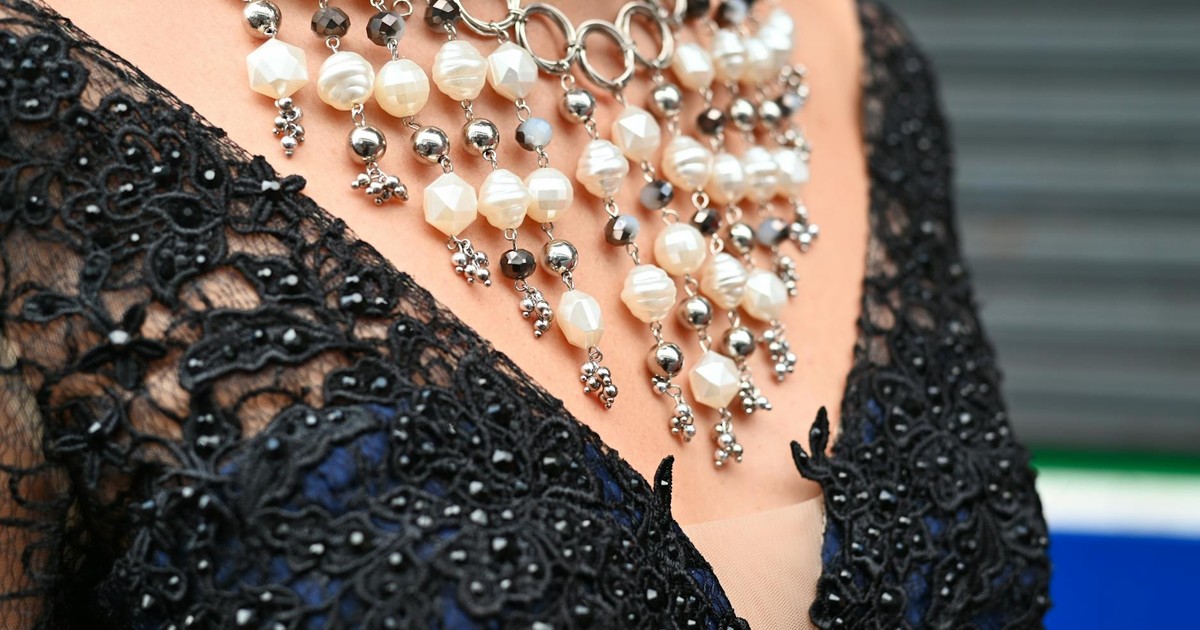 Detailed shot of an intricate pearl necklace on a black lace dress for fashion and accessory focus.