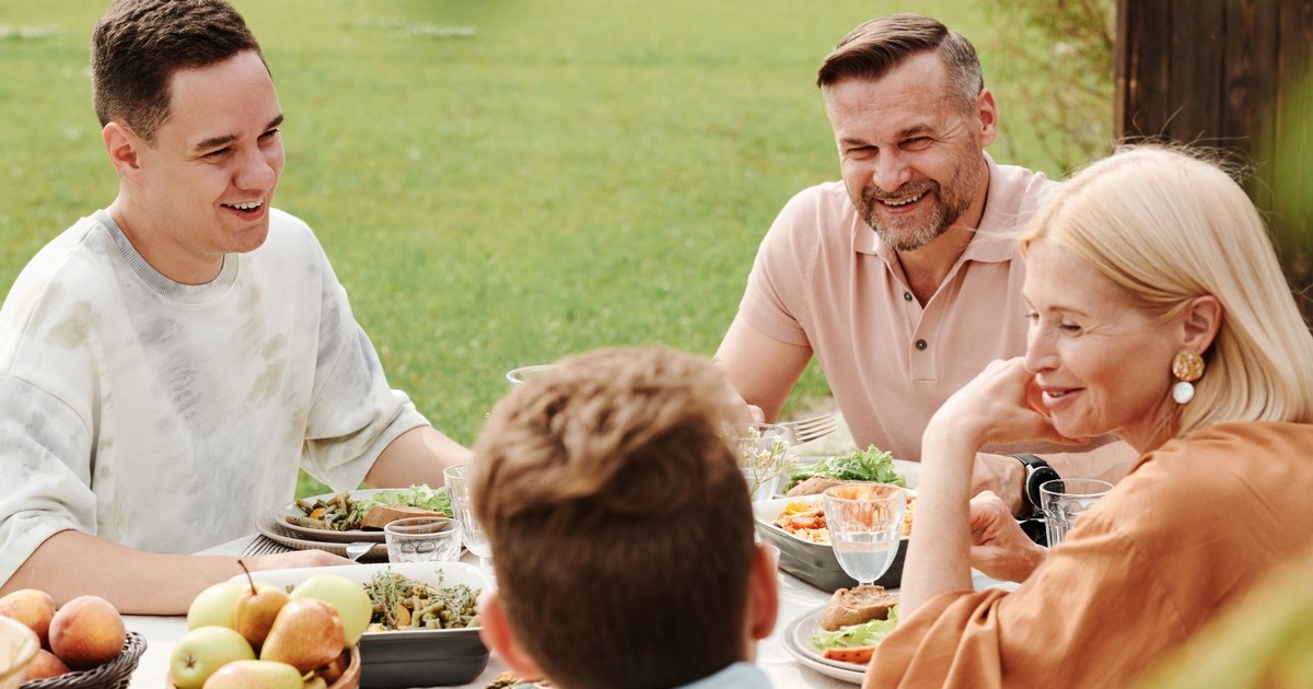A cheerful family enjoying a meal together outdoors, sharing laughter and warmth.