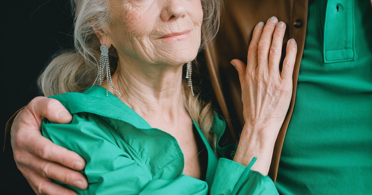 A warm embrace captures an elderly woman in green, exuding love and comfort.