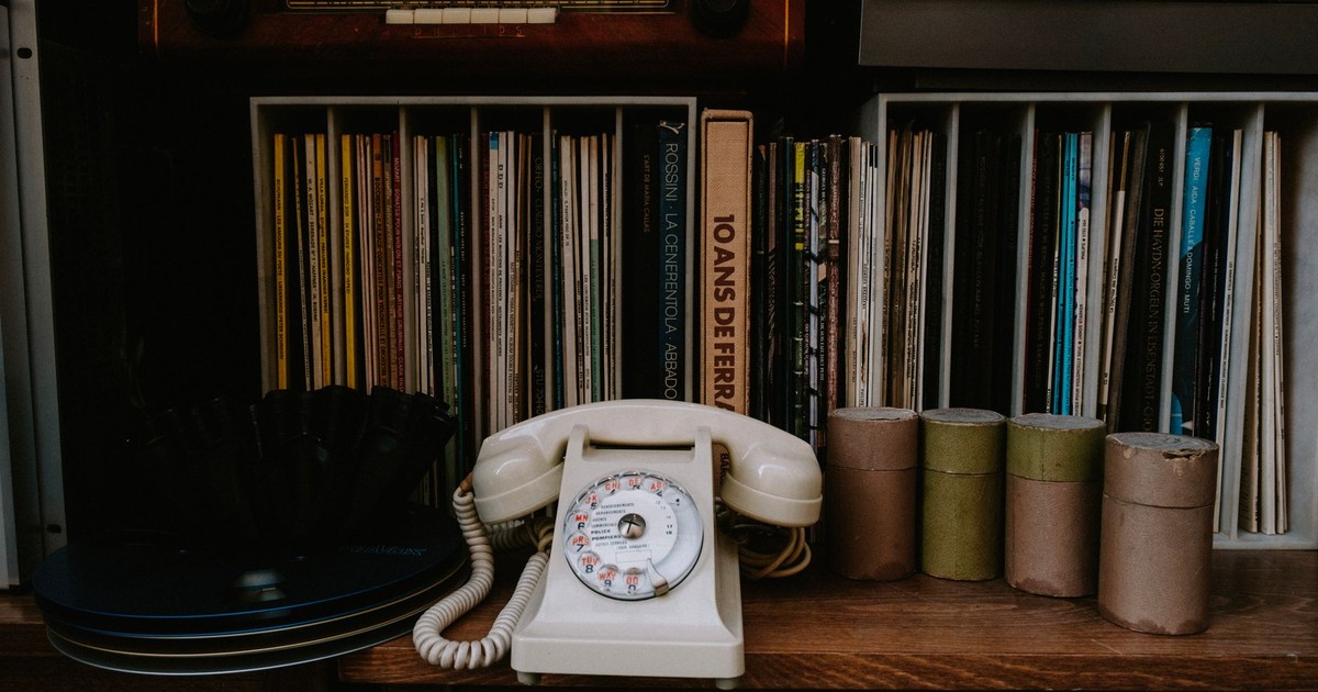 A nostalgic bookshelf featuring a vintage rotary phone and classic literature for a retro vibe.