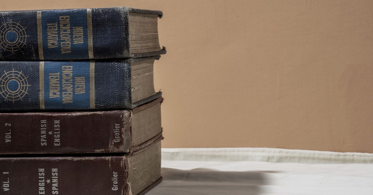A stack of old encyclopedias and dictionaries with copy space on a neutral background.