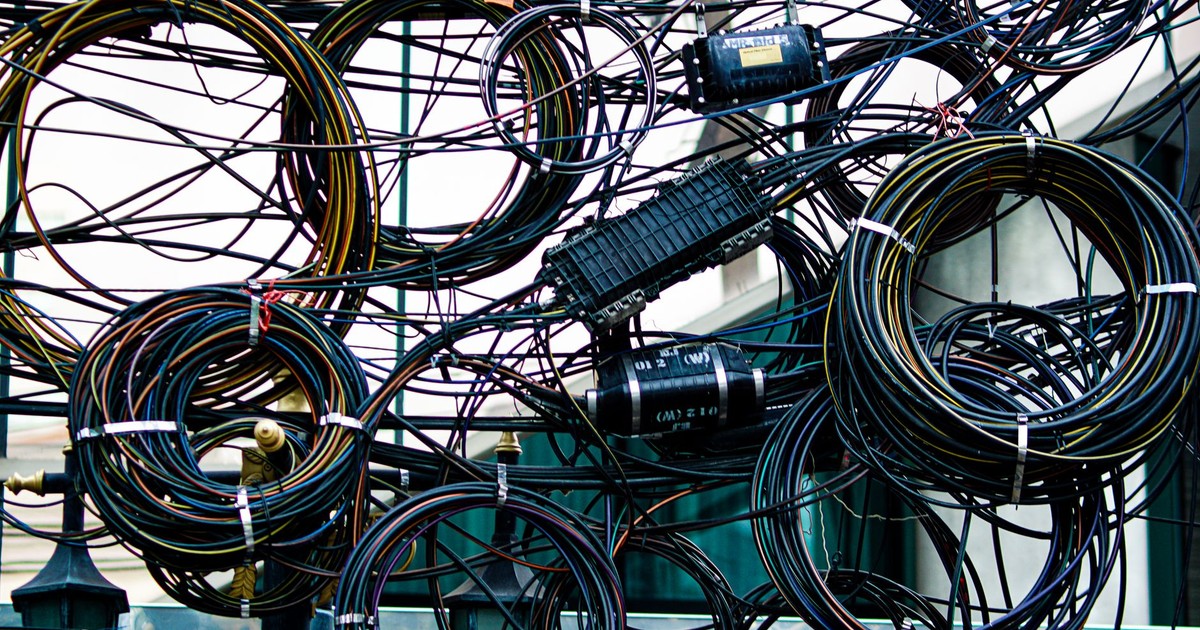 Intricate network of tangled power and communication cables outdoors.