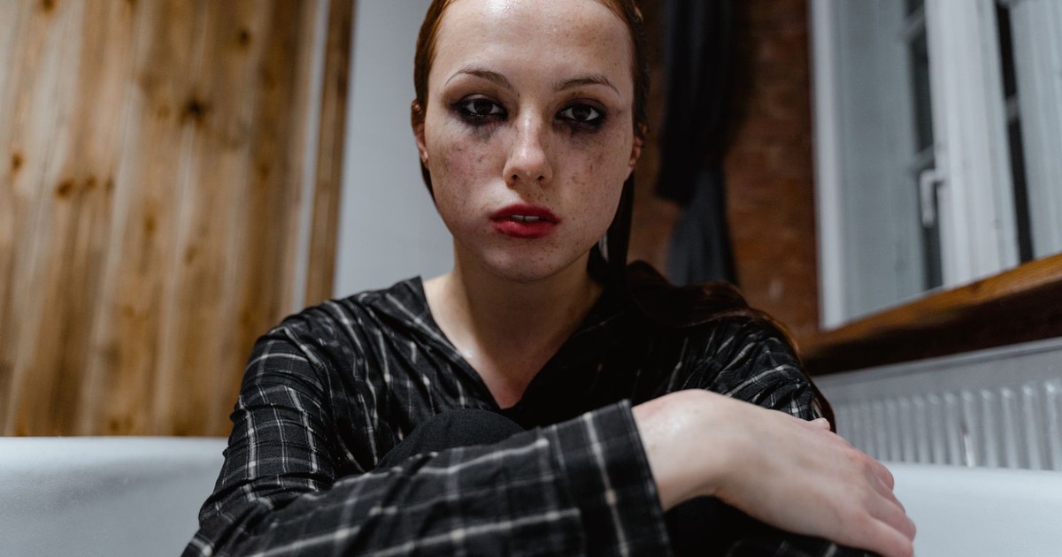 Woman sitting indoors looking thoughtful and emotional, reflecting solitude and calmness.