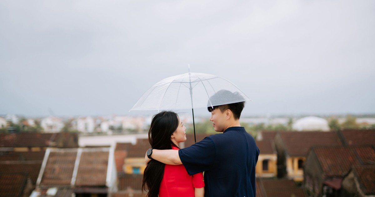 A couple embraces under a clear umbrella, enjoying a romantic moment outdoors.