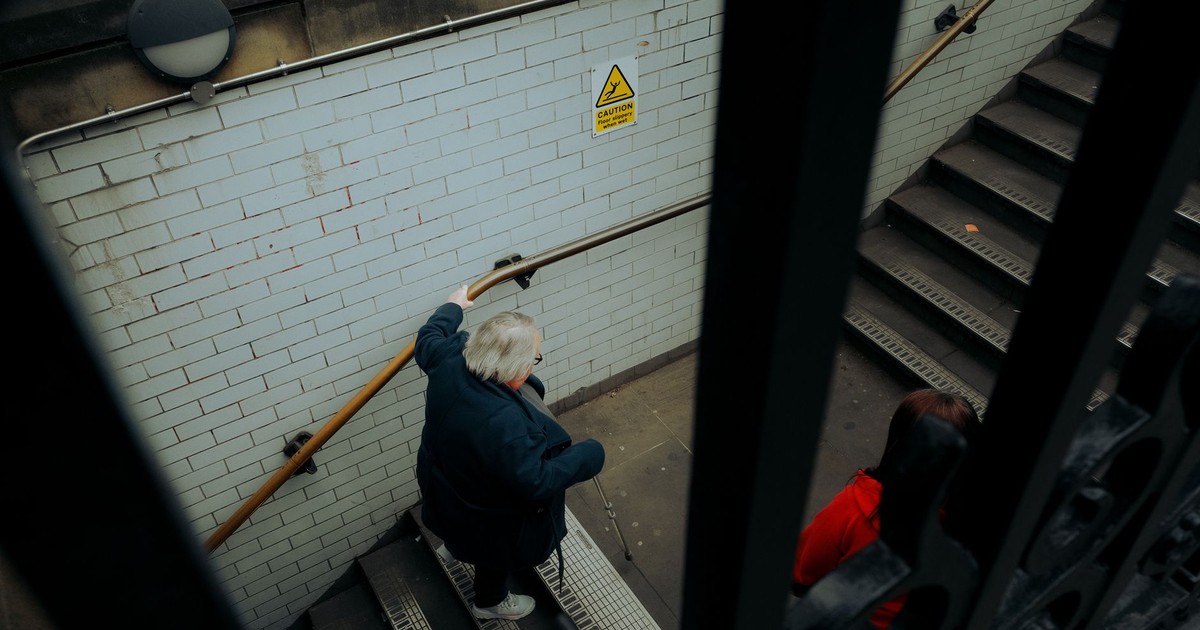 Elderly woman descending urban subway stairs, captured from a high angle view.