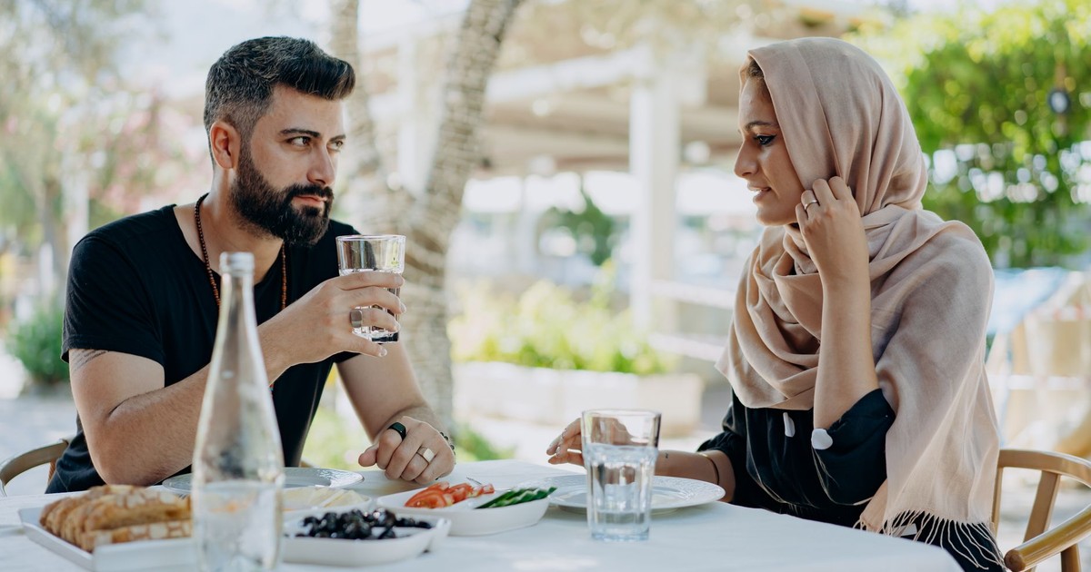 A couple shares a meal and conversation at an outdoor restaurant, capturing a warm and relaxed atmosphere.