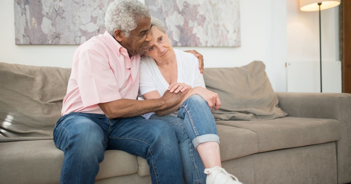 Senior couple embracing warmly on a sofa at home, showcasing love and togetherness.