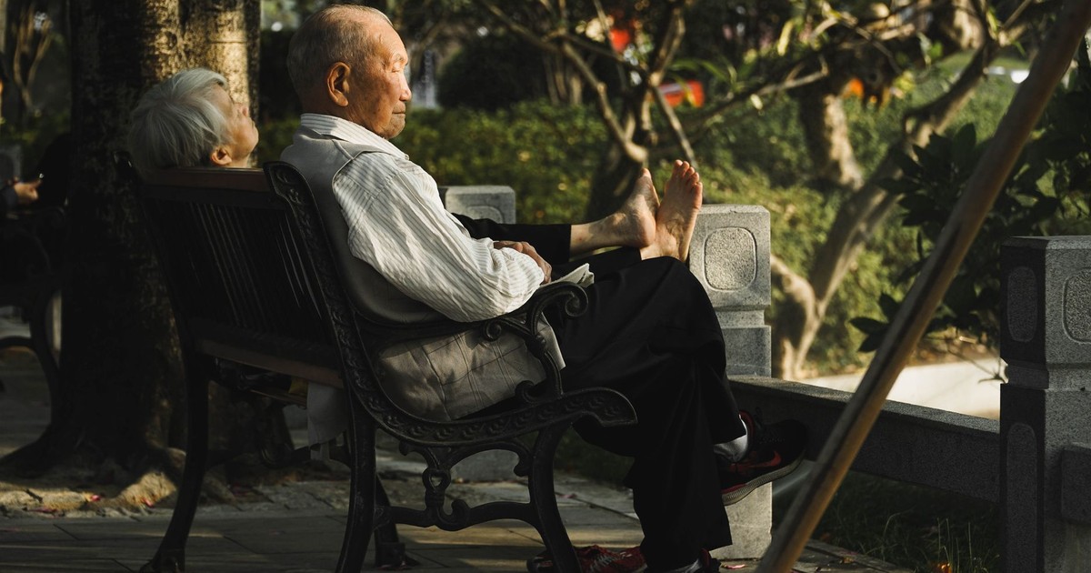 Senior couple enjoying a peaceful moment on a park bench surrounded by fall foliage.