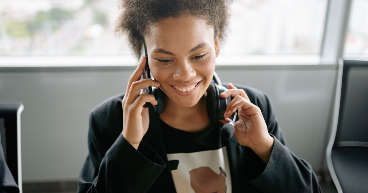 A cheerful call center agent talking on the phone with a headset.