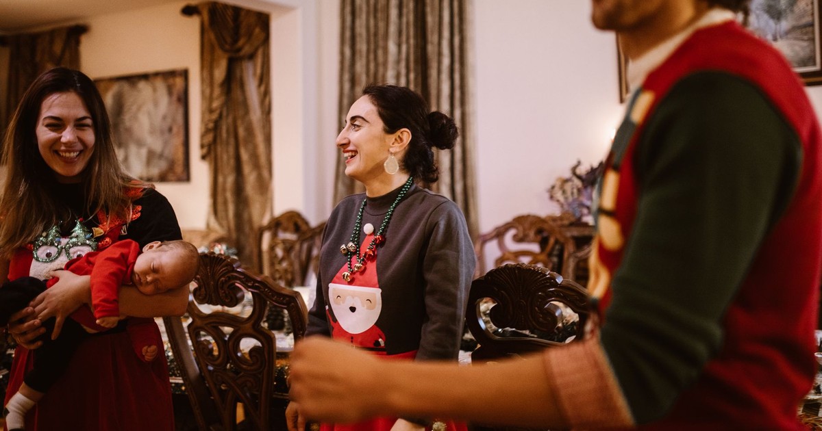 A joyful family gathering celebrating Christmas indoors with festive sweaters.