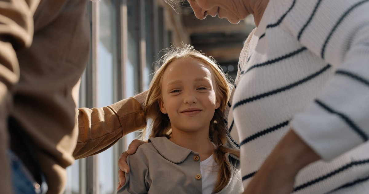 A joyful girl embraced by her loving grandparents, smiling and bonding together.