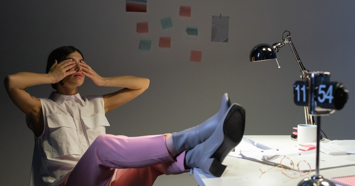 Overworked woman takes a break at her desk, showing exhaustion and relaxation