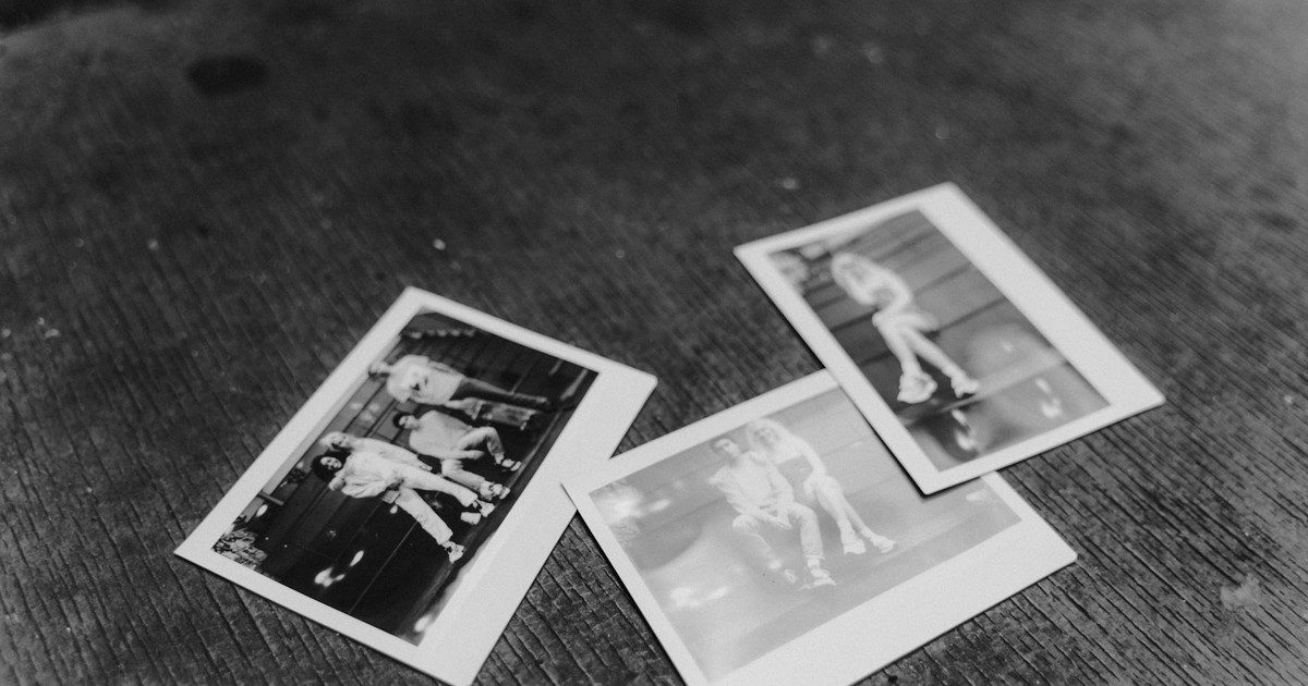 A collection of monochrome instant photos laid on a textured wooden surface, evoking nostalgia.