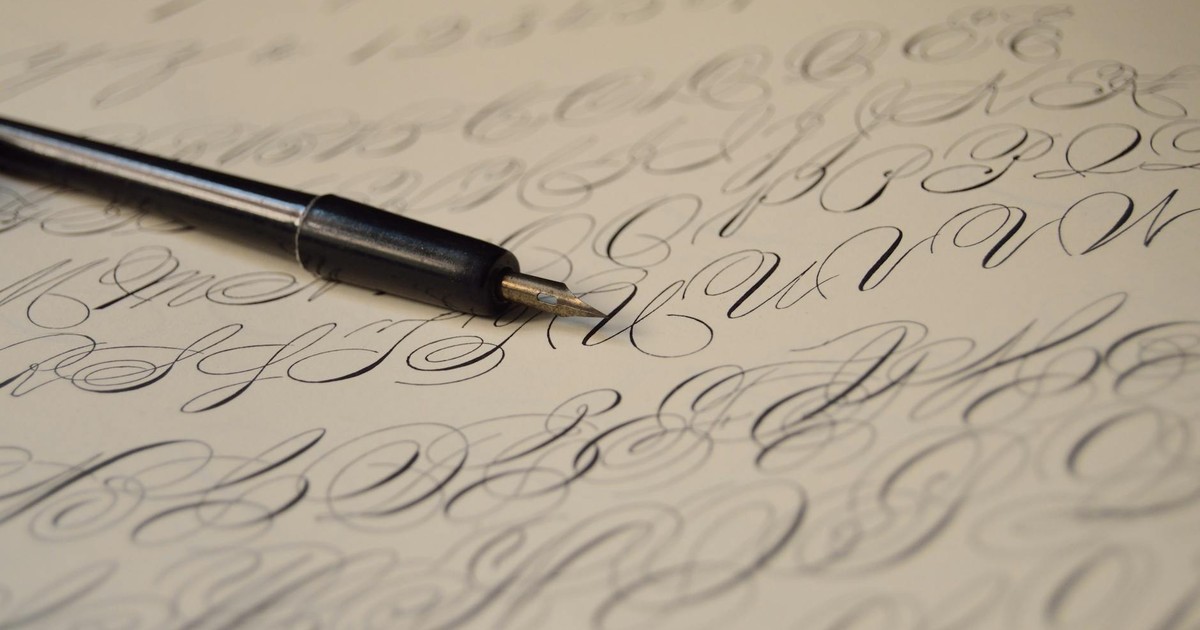 Close-up of elegant calligraphy handwriting using a fountain pen on paper, showcasing artistic lettering.