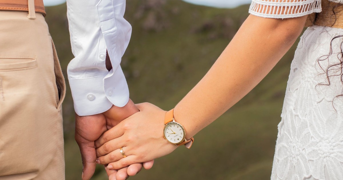 A romantic close-up of a couple holding hands outdoors, symbolizing love and connection.