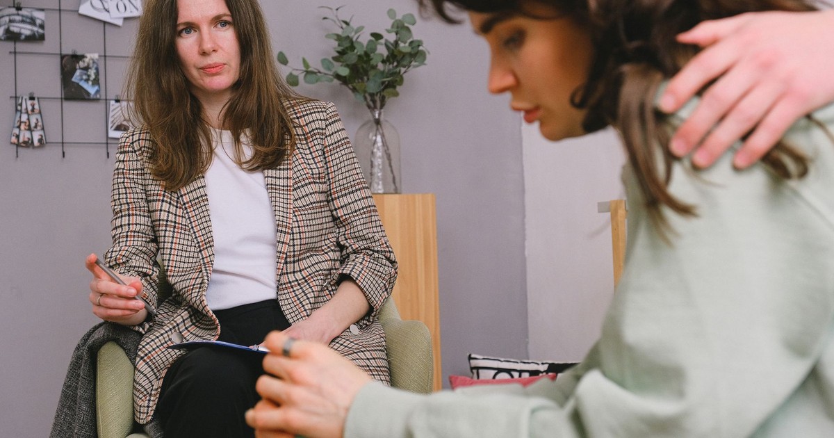 Crop faceless male supporting pondering female with dark hair sharing problems with professional psychologist in daytime