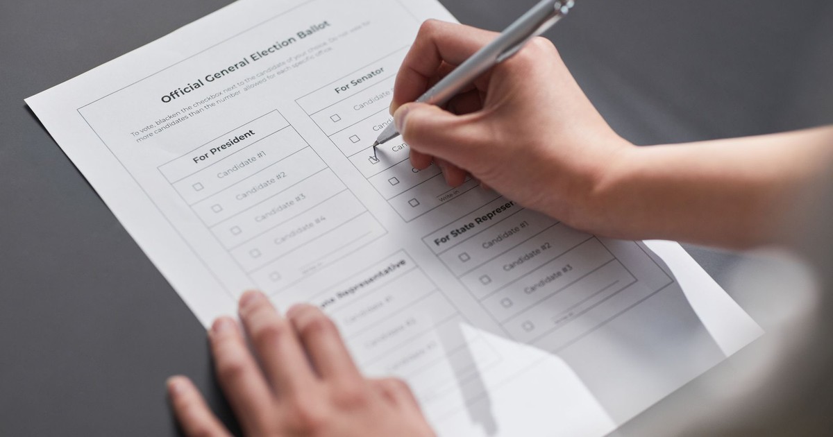 A close-up image of a hand marking an official election ballot with a pen, representing democratic voting.