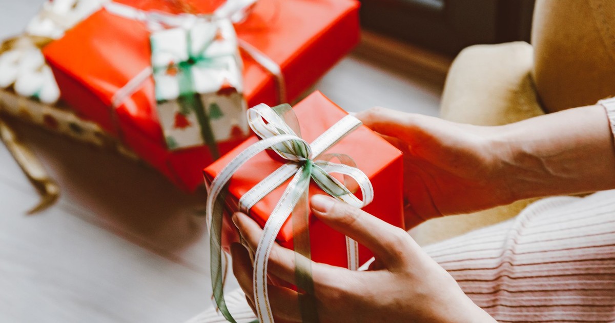 Close-up of hands holding a wrapped Christmas gift tied with ribbon, capturing the festive mood.