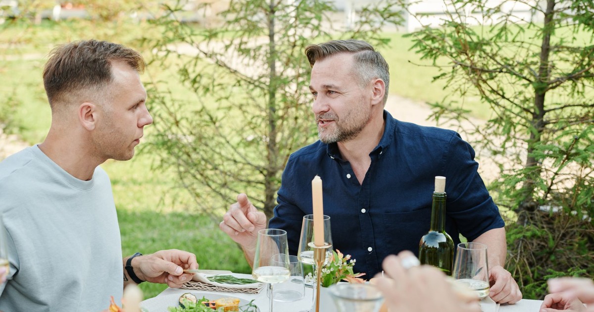 Group of friends having a relaxed outdoor meal with wine and conversation.