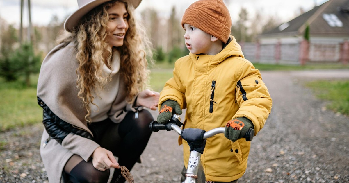 Mother and child spending quality time together with a balance bike in the yard, enjoying a fun outdoor activity.