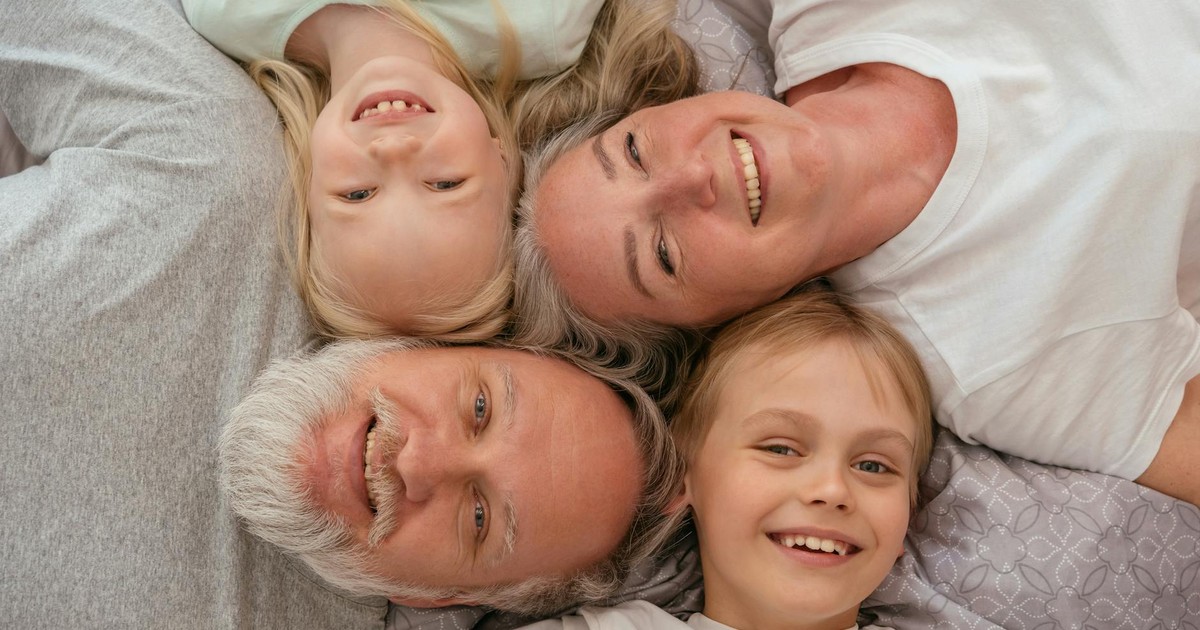 A joyful multigenerational family lying down and smiling together, displaying warmth and affection.