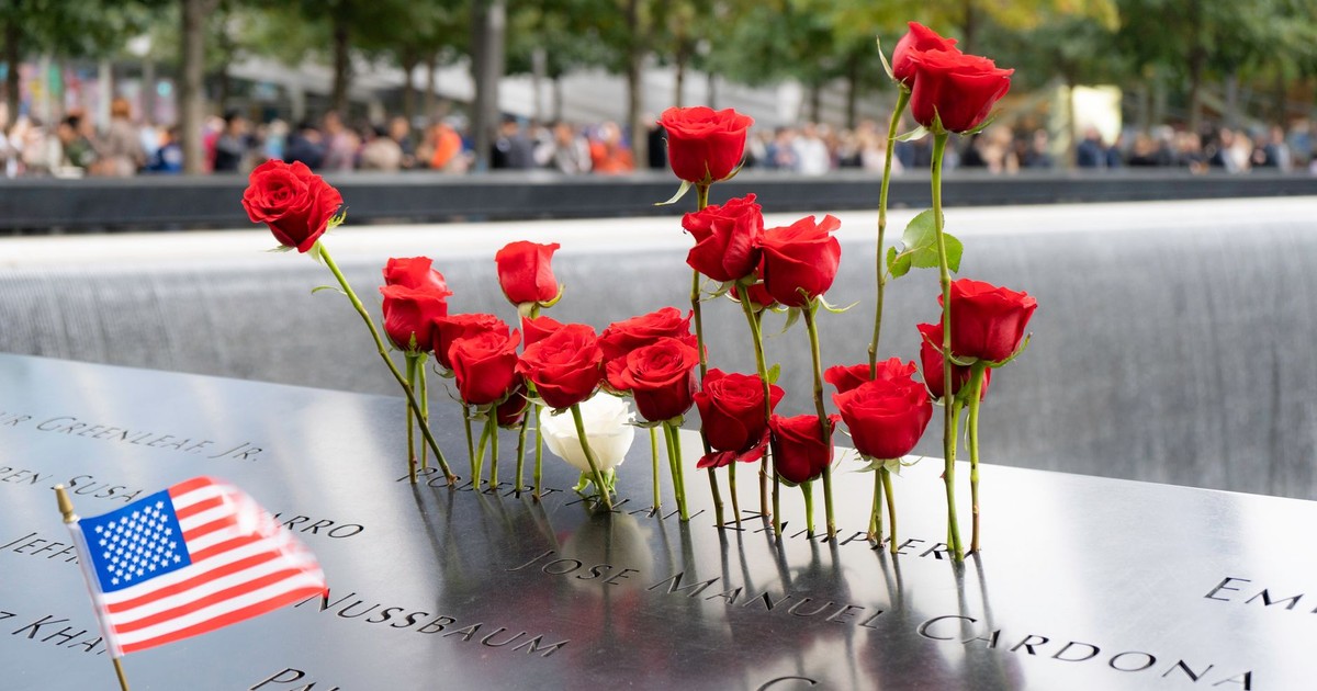 Red roses and American flag at 9/11 Memorial in New York City, reflecting remembrance.