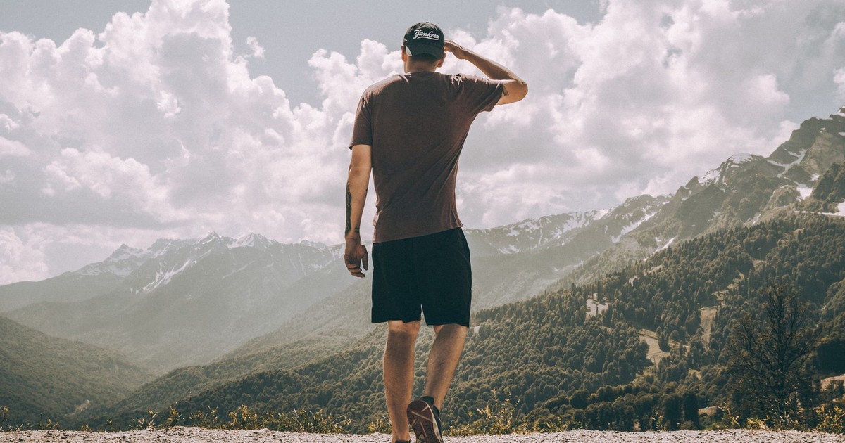 A man enjoys mountain hiking with stunning views of peaks and clouds.