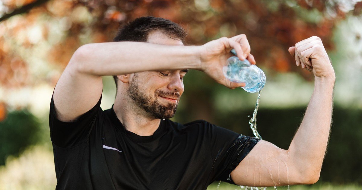 Man pouring water over himself during an outdoor workout, showing refreshment and hydration.