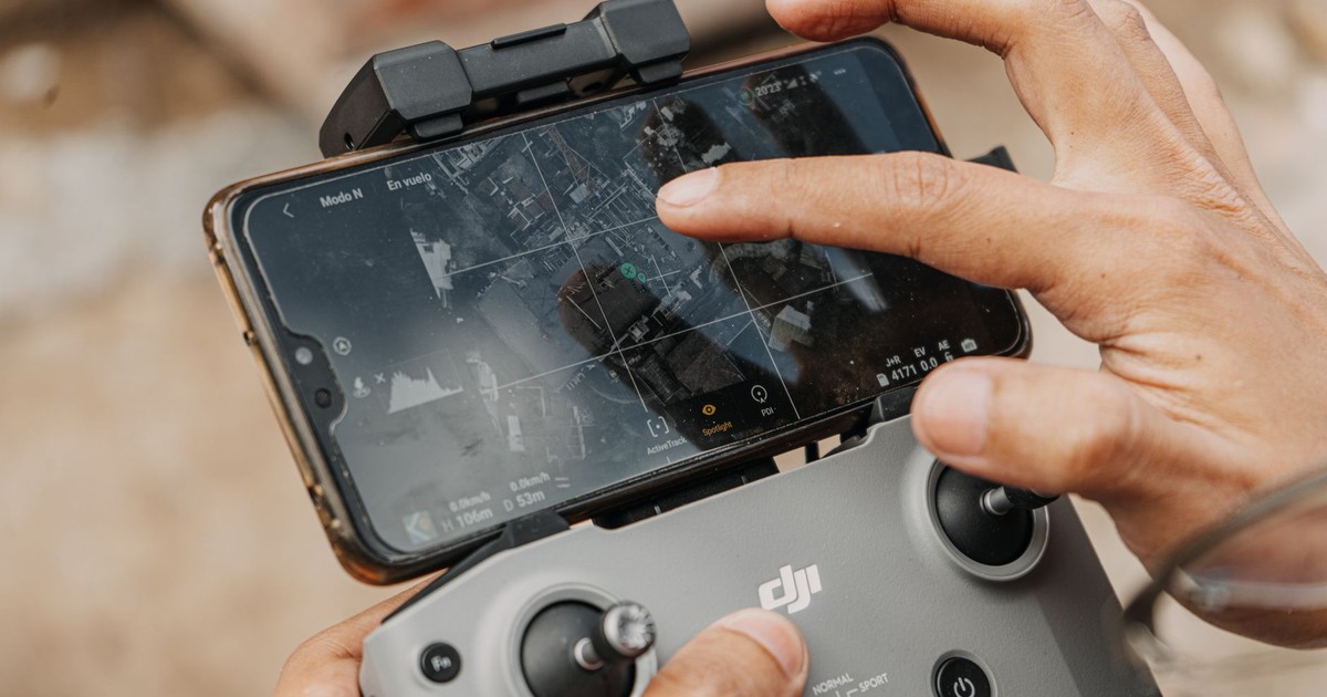 Hands manipulating DJI drone controller with smartphone, showcasing navigation technology.