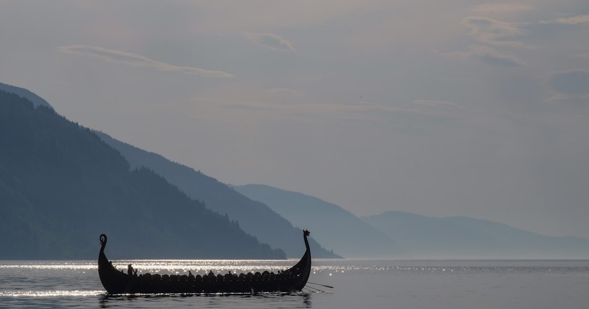 a long boat with two people in it on a lake