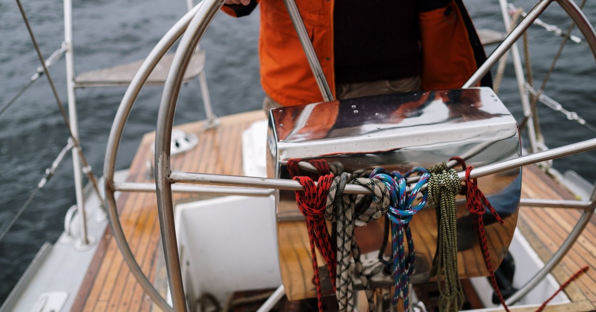 Close-up of a sailor holding the helm of a sailboat, navigating the open sea.
