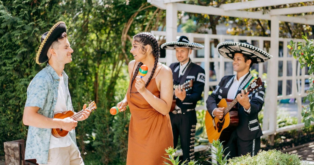 Group enjoying traditional Mexican music outdoors with sombreros and instruments.