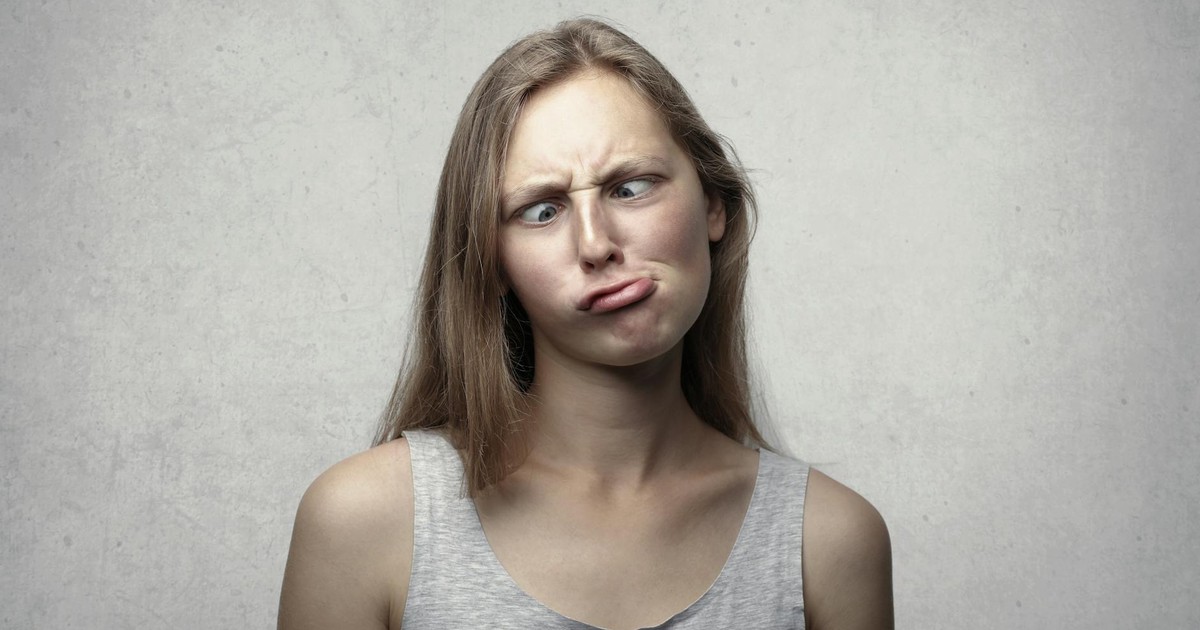 A woman with long hair making a silly expression, adding humor to an otherwise plain gray background.
