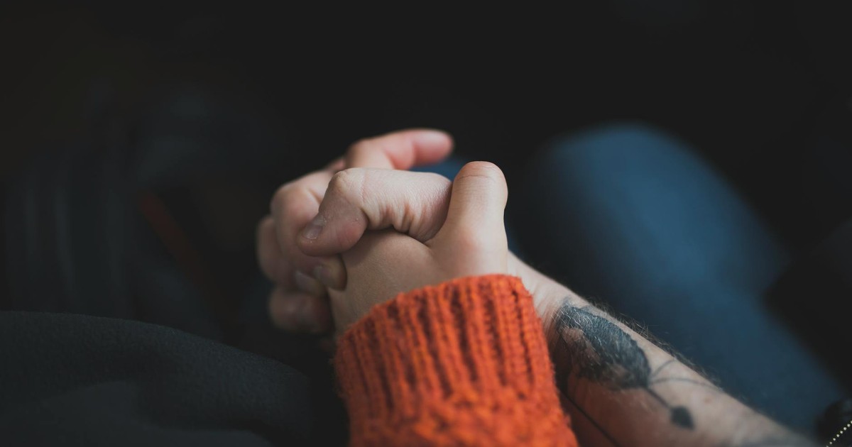 Two hands holding each other, symbolizing love and support with a warm tone.