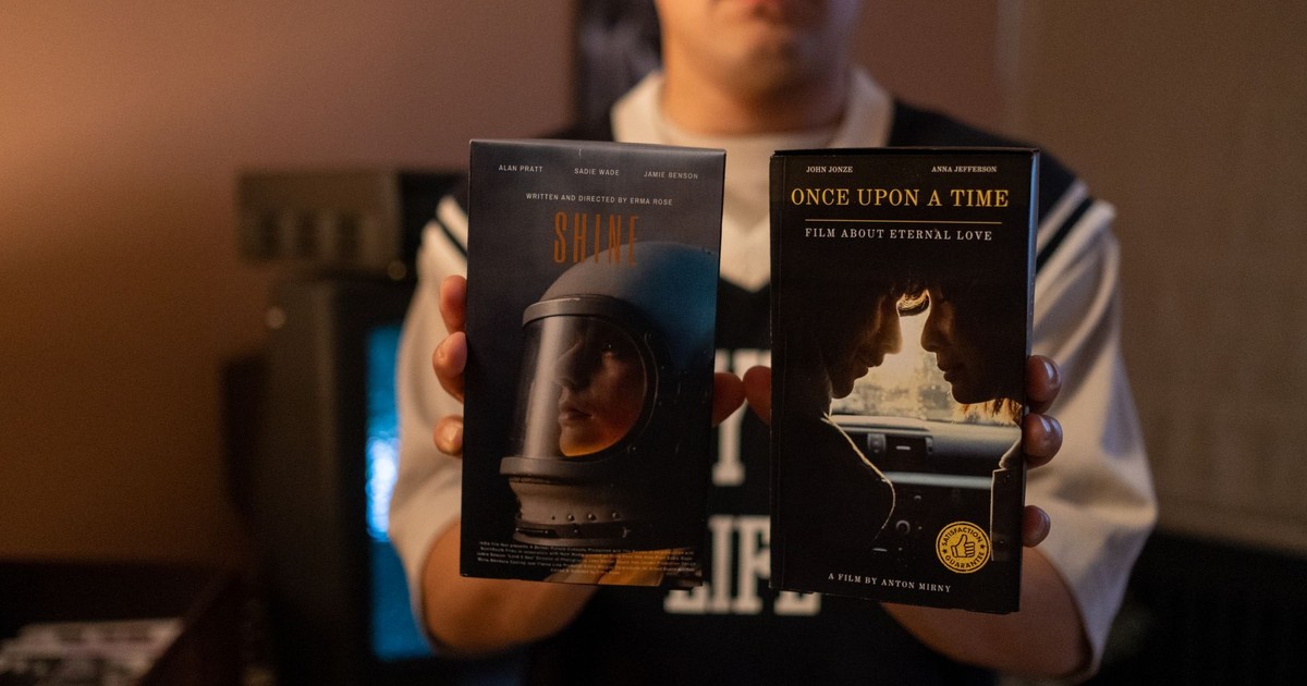 A person holding vintage VHS tapes in a cozy indoor setting.