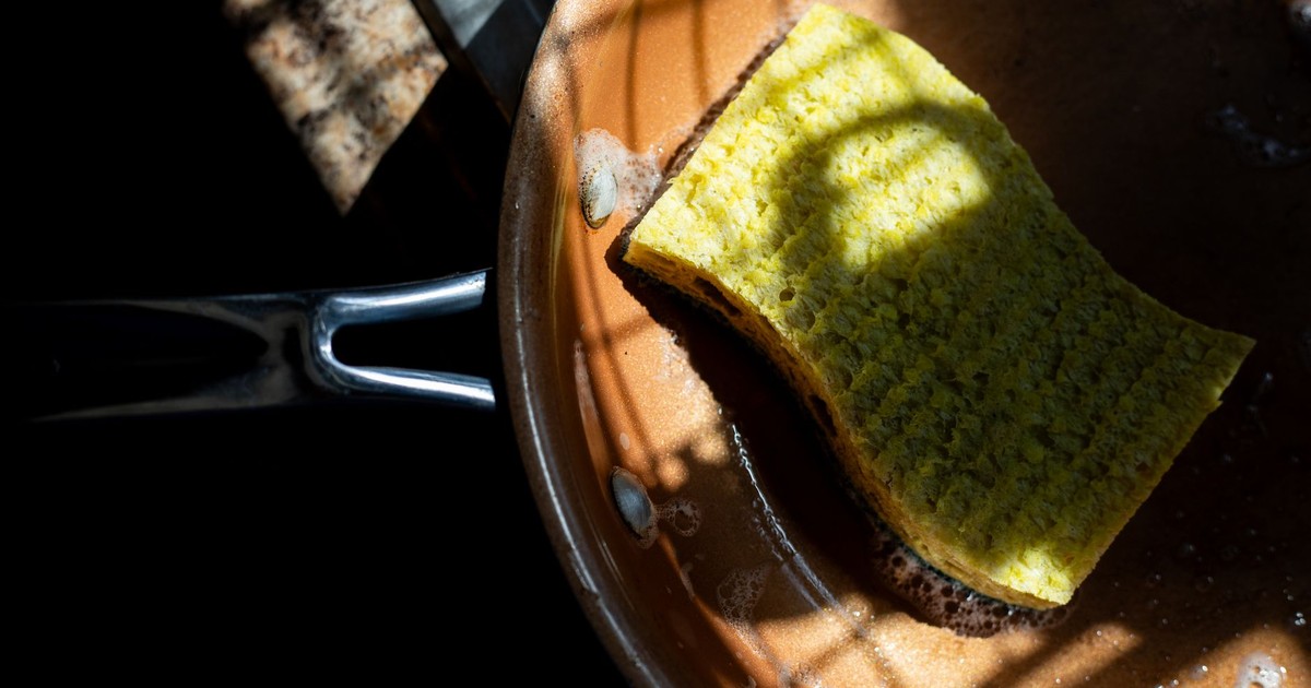 A yellow sponge rests in a copper pan, lit by dramatic shadows. Ideal for cleaning themes.