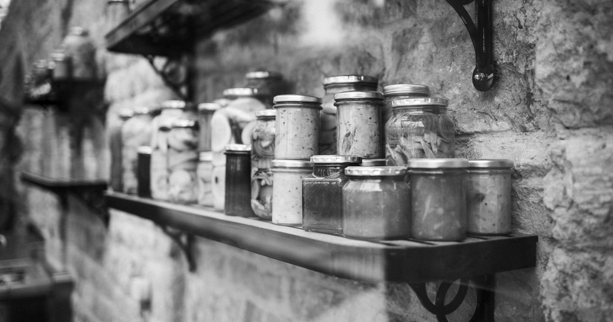Black and white image of glass jars on rustic shelves indoors.